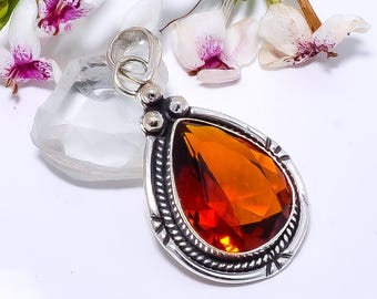 May include: A silver pendant with an amber teardrop-shaped gemstone. The pendant has a detailed silver design around the gemstone.