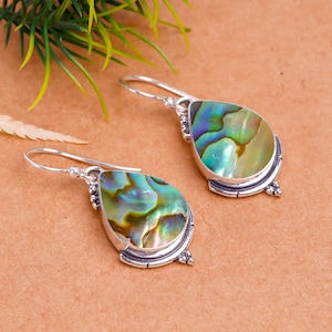 May include: A pair of silver dangle earrings with iridescent abalone shell teardrop-shaped stones.