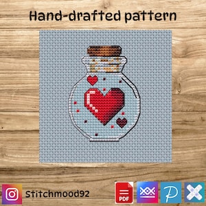 Puede incluir: Patrón de punto de cruz que muestra un tarro de cristal con tapón de corcho, lleno de un corazón rojo pixelado y corazones rojos más pequeños. El texto "Hand-drafted pattern" está en la parte superior y el nombre de Instagram "Stitchmood92" en la parte inferior.