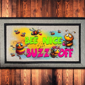 May include: A rectangular doormat with a black border and a light-colored center featuring cartoon bees and the text "BEE NICE OR BUZZ OFF" in bright green and pink letters. The design includes multiple bees with colorful details.