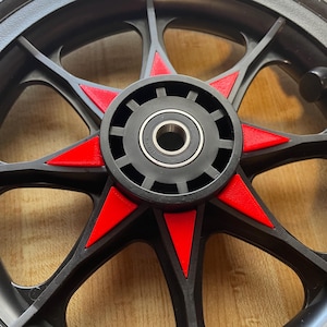 Può includere: Ruota nera con accenti a forma di stella rossa. La ruota ha un mozzo nero con un cuscinetto argentato.