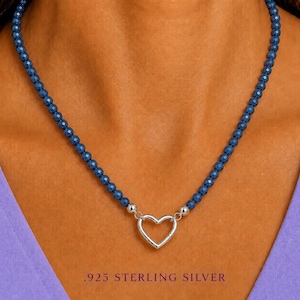 May include: A necklace featuring a strand of small, faceted dark blue beads. The necklace includes a central silver-coloured heart-shaped clasp. The text .925 STERLING SILVER is printed at the bottom of the image, indicating the metal composition.