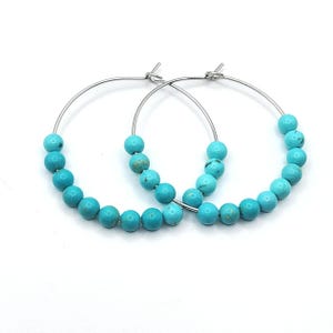 May include: A pair of silver hoop earrings with turquoise beads. The earrings are simple and elegant, and would make a great gift for any occasion.