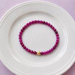 Red ruby 4mm bracelet laid on a white plate.