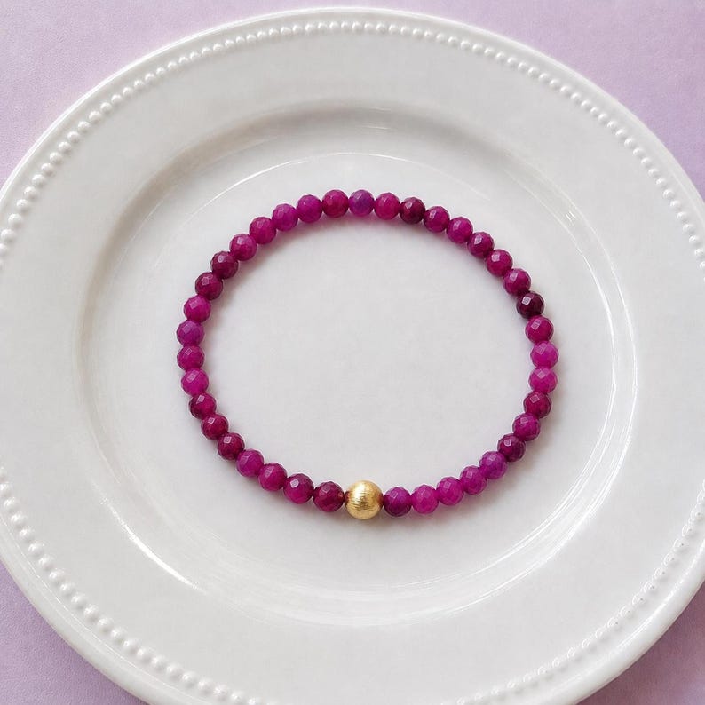 Red ruby 4mm bracelet laid on a white plate.