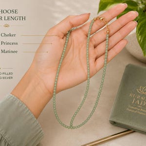 May include: A light green beaded necklace with a gold-filled sterling silver clasp. Text on the image reads: CHOOSE YOUR LENGTH, 16" Choker, 18" Princess, 24" Matinee, 14K GOLD FILLED STERLING SILVER, BURMESE JADE, Timeless Beauty, Natural Harmony.