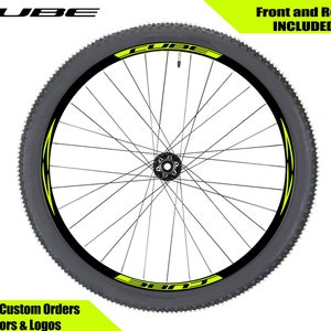 May include: A black bicycle wheel with a yellow and black rim sticker that says "CUBE". The sticker is on both sides of the wheel. The text "Front and Rear INCLUDED" is in the upper right corner of the image.