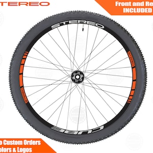 May include: A black mountain bike wheel with an orange and black rim stripe. The wheel has a black hub and black spokes. The rim is labeled "STEREO" in white lettering. The text "Front and Rear INCLUDED" is in the upper right corner of the image.