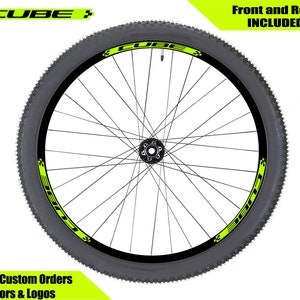May include: A black bicycle wheel rim with a yellow "CUBE" logo sticker on the side. The sticker is on both sides of the wheel. The text "Front and Rear INCLUDED" is in the upper right corner of the image.