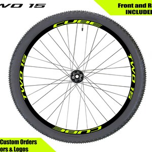 May include: A black bicycle wheel with a yellow "TWO 15" decal on the side. The decal is on a black background with a white outline. The wheel is for a mountain bike.