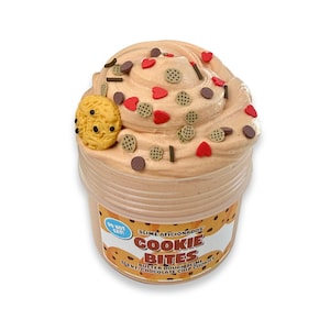 May include: A container of "Cookie Bites" slime. The light brown slime is decorated with small, round chocolate chips, heart-shaped sprinkles, and a yellow cookie. The container has a label with the text "Slime Aficionados" and "Cookie Bites".