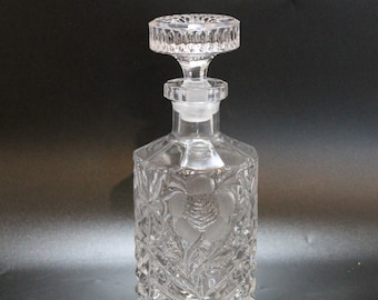 May include: A clear glass decanter with a cut glass design and a stopper. The decanter has a floral pattern.