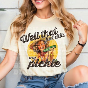 Pu&ograve; includere: Una maglietta gialla con una grafica in stile vintage di una donna che tiene un cetriolo. Il testo sulla maglietta recita "Well that just dills my pickle".