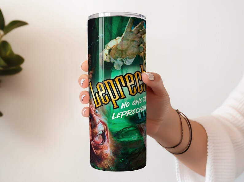 May include: A stainless steel tumbler with a green, black, and yellow design featuring a character from the film "Leprechaun" with the text "Leprechaun" and "No one tricks the Leprechaun".
