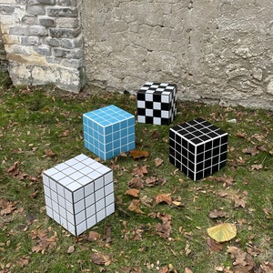 May include: Four square ceramic stools with different checkered patterns. The stools are blue and white, black and white, and two different shades of gray and white.