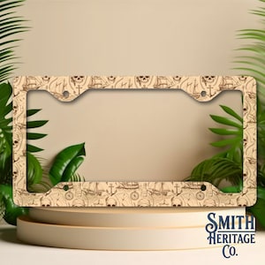 May include: A rectangular license plate frame featuring a repeating brown line art pattern of pirate-themed imagery including skulls, sailing ships, anchors, compasses, and treasure maps on a light beige background with four mounting holes.