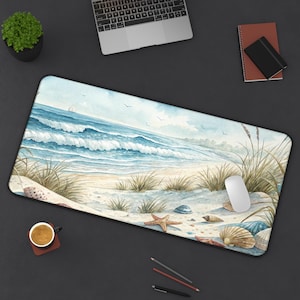 May include: A rectangular desk mat featuring a watercolor beach scene with blue waves, sand, and seashells. The mat includes a white computer mouse, a cup of coffee, and a laptop.