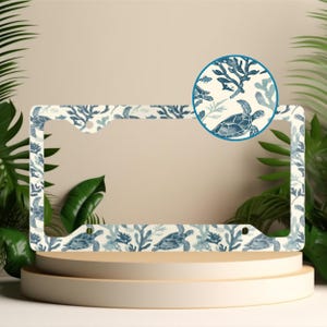 May include: White metal license plate frame with a blue and white sea turtle and coral design.