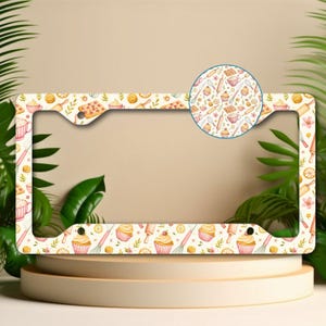 May include: A decorative license plate frame with a repeating pattern of baking-themed illustrations. The design includes cupcakes, rolling pins, whisks, and lemons on a cream-colored background. A circular inset shows a detailed view of the pattern.