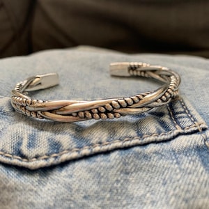 Peut inclure: Un bracelet jonc en argent tressé avec un motif torsadé.