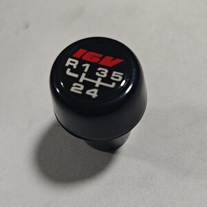 May include: Black gear shift knob with a red "16V" logo and white numbers and letters indicating gear positions: "R", "1", "3", "5", "2", "4".
