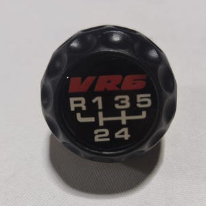 May include: Black gear shift knob with a red "VR6" logo and white gear pattern. The gear pattern shows "R135" and "LHL" with "24" at the bottom.