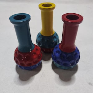 Pu&ograve; includere: Tre piccoli vasi in ceramica con un design a pallina da golf. I vasi sono dipinti in diversi colori: rosso, blu e giallo. Ogni vaso ha un colore diverso nella parte superiore e inferiore.