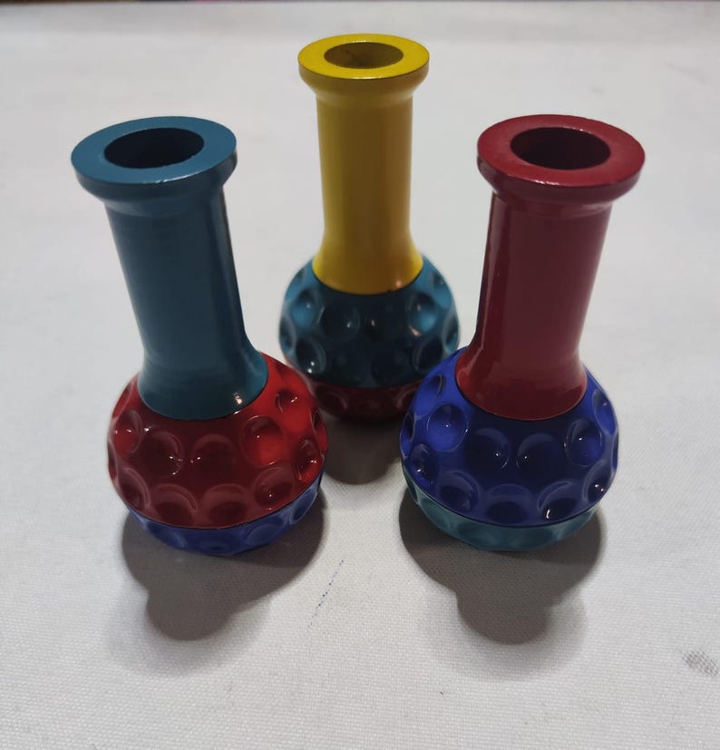 Pu&ograve; includere: Tre piccoli vasi in ceramica con un design a pallina da golf. I vasi sono dipinti in diversi colori: rosso, blu e giallo. Ogni vaso ha un colore diverso nella parte superiore e inferiore.