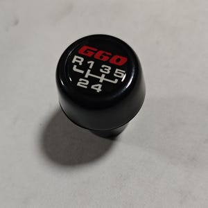 Può includere: Pomello del cambio nero con logo G60 rosso e bianco e numeri bianchi 1, 3, 5, R, 2 e 4.