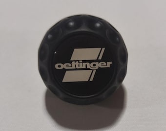 May include: Black golf ball with a white "Oettinger" logo.