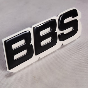 May include: Black BBS logo on a white background. The logo is raised and has a glossy finish.