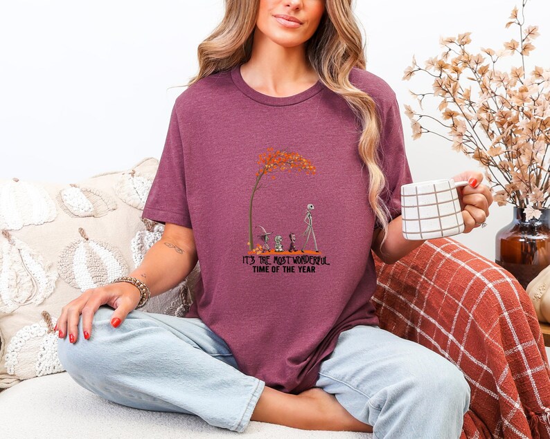 May include: Burgundy t-shirt with a graphic featuring a tree with orange leaves and characters from The Nightmare Before Christmas. The text "IT'S THE MOST WONDERFUL TIME OF THE YEAR" is below the graphic.