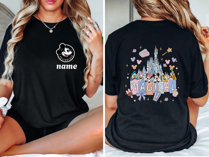 May include: Black t-shirt featuring a Mickey Mouse graphic with the text "PASS HOLDER" and "name" on the front. The back of the shirt displays a colorful illustration of Disney characters and a castle with the word "MAGICAL".