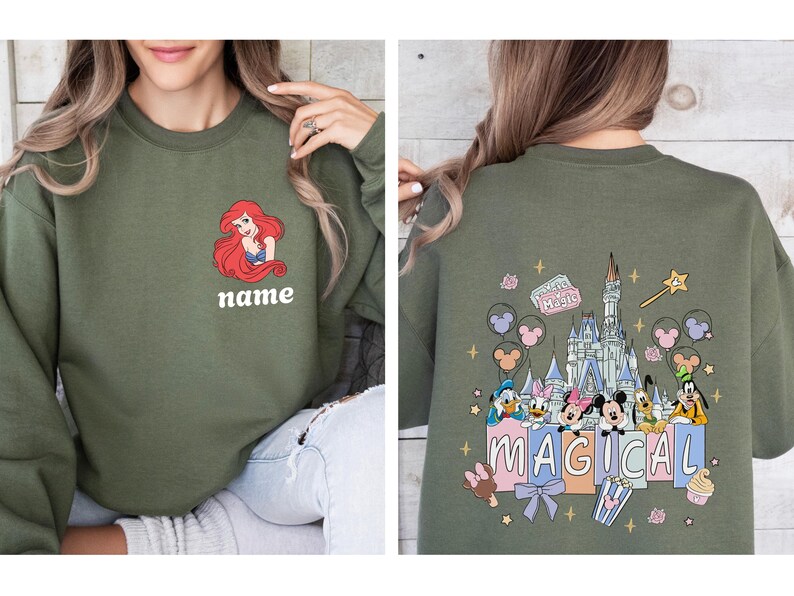 May include: Olive green sweatshirt featuring a cartoon image of Ariel with the word "name" below. The back of the sweatshirt has a colorful graphic of a castle, Disney characters, and the word "MAGICAL".
