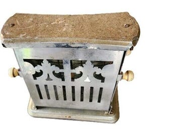 May include: A vintage chrome toaster with a decorative design and two white plastic knobs. The toaster has a worn, aged appearance.