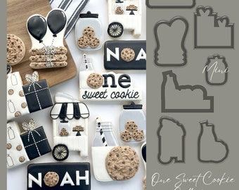 May include: A set of cookie cutters for a first birthday party. The cutters are in the shape of a milk bottle, a cookie jar, a gift box, a cookie cart, a balloon, and a banner that says "One Sweet Cookie".