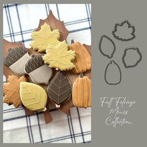 Könnte beinhalten: Ein Satz Ausstecher in Form von Blättern und Kürbissen. Die Ausstecher sind auf einem grauen Hintergrund mit dem Text "Fall Foliage Minis Collection" angeordnet.