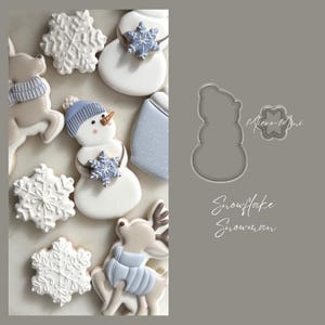 May include: An assortment of winter-themed cookies, including snowmen, snowflakes, and reindeer, decorated with blue and white icing. A snowman-shaped cookie cutter and the words "Snowflake Snowman" are also visible.
