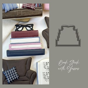 May include: A cookie cutter shaped like a stack of books with glasses on top. The cutter is made of metal and has a gray finish. The text "Book Stack with Glasses" is written below the cutter.