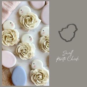 May include: A set of six decorated sugar cookies shaped like chicks with rosettes. The cookies are decorated with white icing and a rosette made of beige icing. The cookies are arranged on a white surface. A cookie cutter shaped like a chick is shown in the upper right corner of the image. The text "Small Rosette Chick" is written below the cookie cutter.