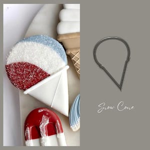 Op de afbeelding: Close-up van versierde koekjes in de vorm van een sneeuwkegel, een ijslolly en een ijshoorntje. De sneeuwkegelkoek heeft rode, witte en blauwe hagelslag. De afbeelding bevat ook een metalen sneeuwkegelkoekjesuitsteker en de tekst "Snow Cone".