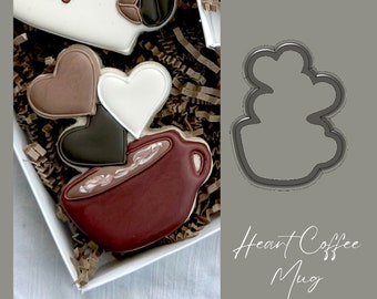 May include: A red heart-shaped coffee mug cookie cutter. The cutter is made of metal and has a smooth, shiny finish. The cutter is shown next to a decorated cookie in the shape of a coffee mug.