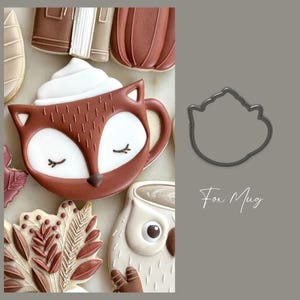 May include: A collection of decorated cookies, including a fox-shaped mug with white whipped cream, a leaf, a pumpkin, and an owl. The fox mug is brown and white with closed eyes. The text "Fox Mug" is in the image.