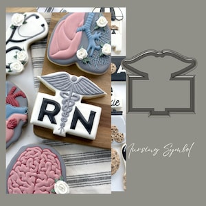 May include: A set of cookie cutters featuring medical symbols, including a stethoscope, lungs, a brain, a heart, and the letters RN with a caduceus. The cutters are made of metal and are designed to cut out cookies in the shape of these symbols. The cutters are shown on a wooden chopping board with a grey and white striped background.