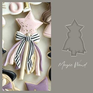May include: A selection of decorated biscuits, featuring a star-shaped biscuit with pink icing and gold sprinkles, and a magic wand biscuit with a black and white striped bow and ribbons. The biscuits are in various shapes and colours.