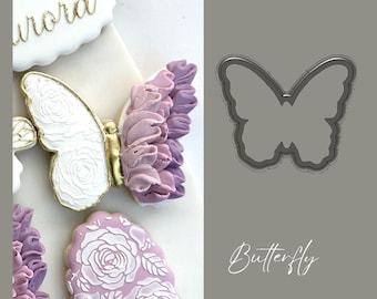 May include: A close-up of a butterfly-shaped cookie cutter. The cutter is made of metal and has a smooth, shiny finish. The cutter is designed to create butterfly-shaped cookies.