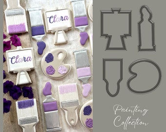 May include: A set of four cookie cutters for making paintbrush, paint tube, palette, and easel cookies. The cutters are made of metal and are shown on a gray background. The text "Painting Collection" is printed below the cutters.
