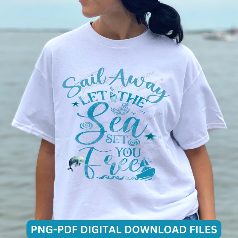 May include: White t-shirt with a blue graphic design that says "Sail Away Let The Sea Set You Free". The graphic includes a sailboat, a dolphin, and seashells.