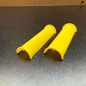 May include: Two yellow plastic pipe covers with a rounded edge and a curved opening on one end.