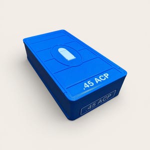May include: A bright blue rectangular container with a raised design on the lid and the text ".45 ACP" printed on the side. The container has a recessed oval shape with a bullet graphic.